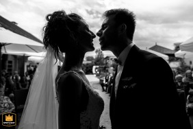 A romantic, sun-drenched moment captures the kiss between the newlyweds at the close of their wedding ceremony in the beautiful surroundings of La Médicée, France, symbolizing the beginning of their life together.